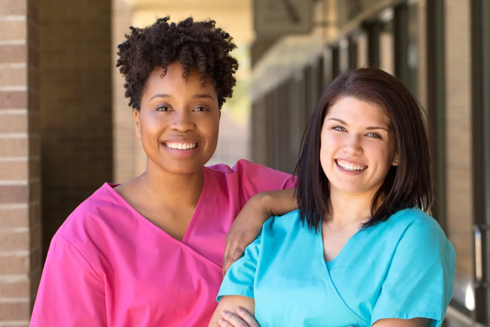 Two women in scrubs smiling for a picture.