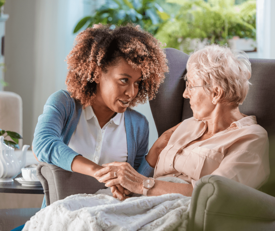 A woman sitting on the arm of an older person.